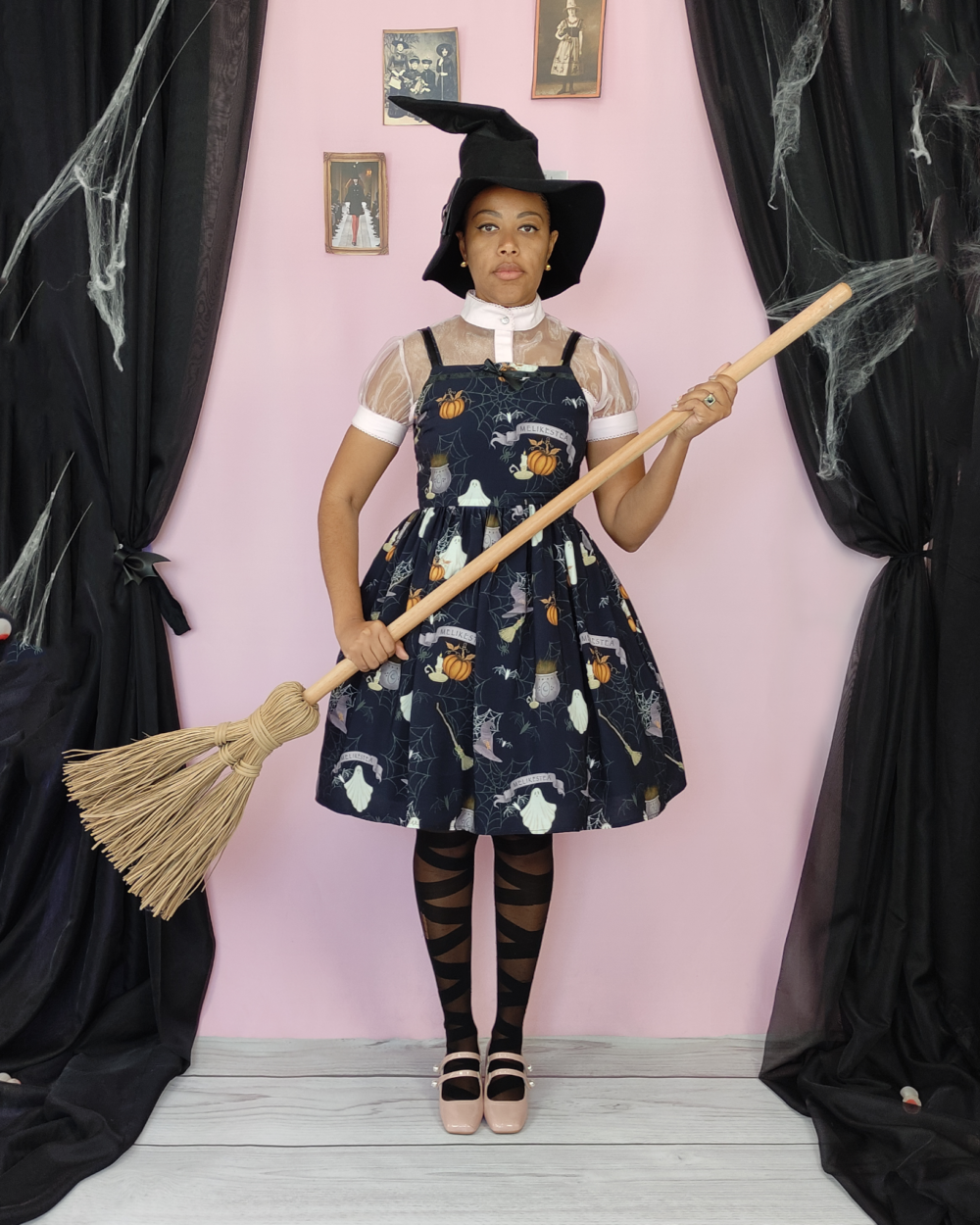 Witch wearing Halloween sleeveless dress in black and holding a broomstick